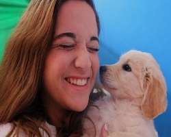She is accompanied by a cute dog in her home.